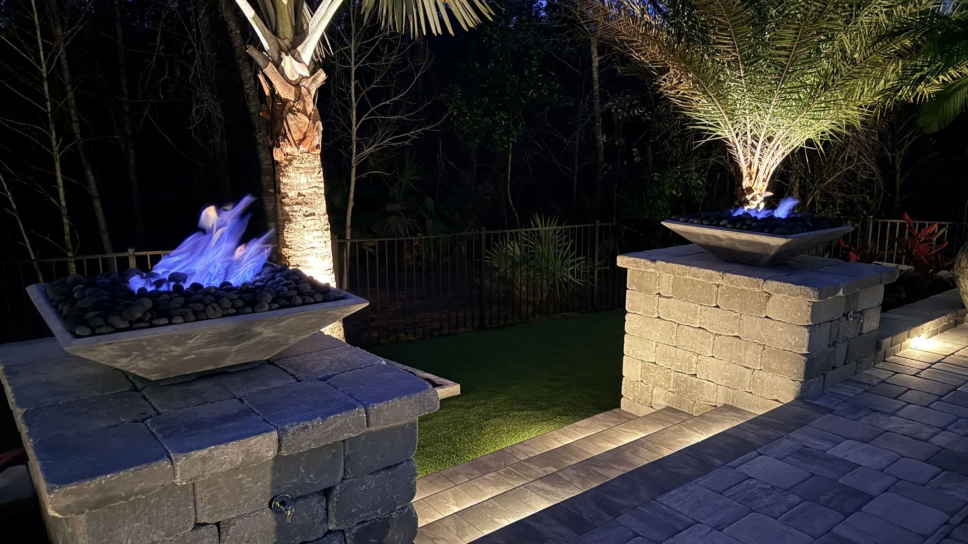 Paver patio with custom fire bowls and landscape lighting at dusk, St. Johns County FL